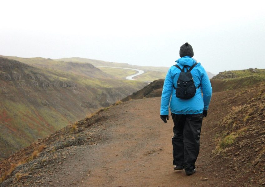 Työnohjaaja kävelemässä polkua pitkin. Kaukana siintää uusi polku.
