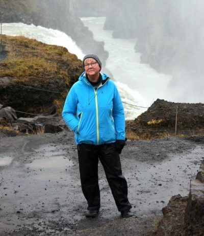 Työnohjaaja Merja Lounela katsoo kameraan ja taustalla on luontomaisema.